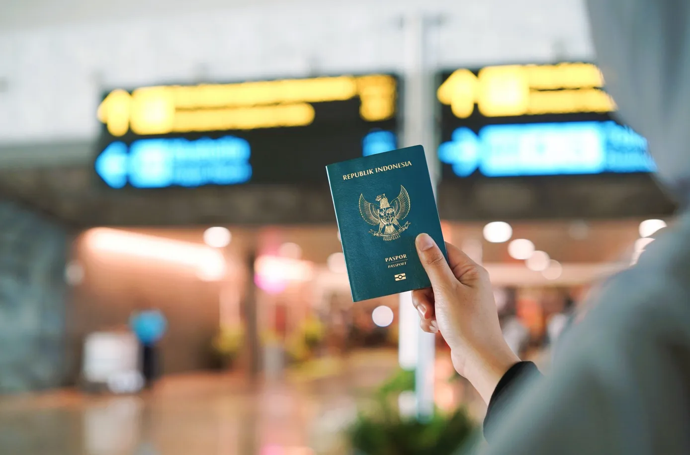Close-up of a hand holding a navy blue British passport with gold Royal Coat of Arms lettering