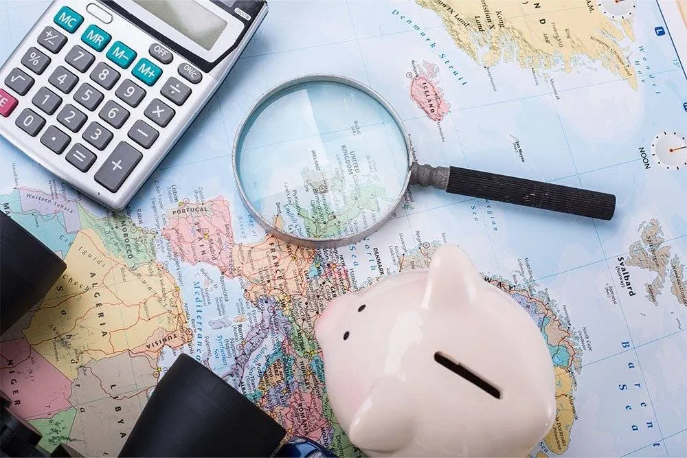 Piggy bank, calculator, magnifying glass and binoculars on a world map — Shutterstock