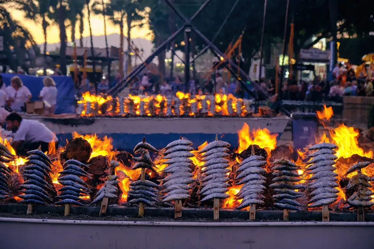 Grilled espetos, skewers of sardines, cooking over an open fire, a popular beachside delicacy in Malaga.