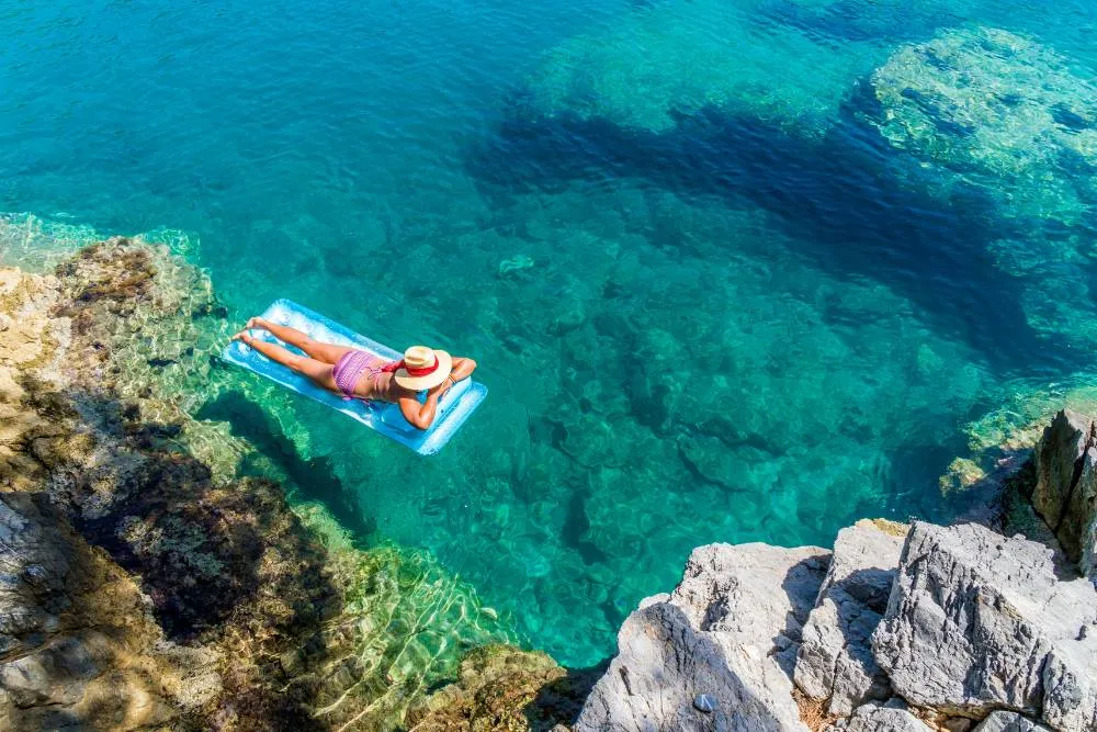 Person on lilo in turquoise sea — Getty Images