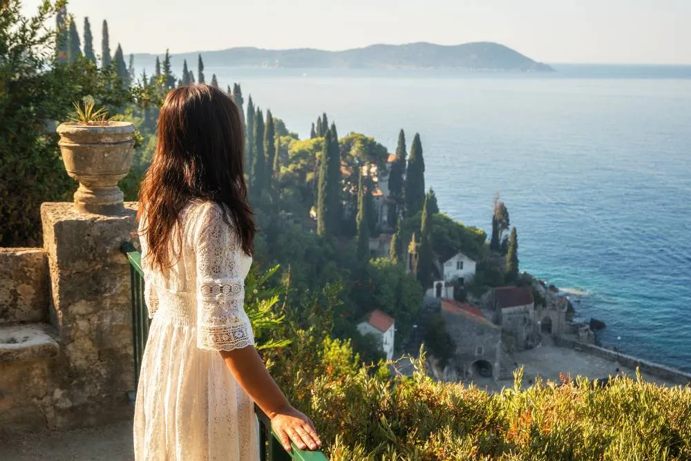Woman standing at Trsteno Arboreteum looking out to sea — Getty Images