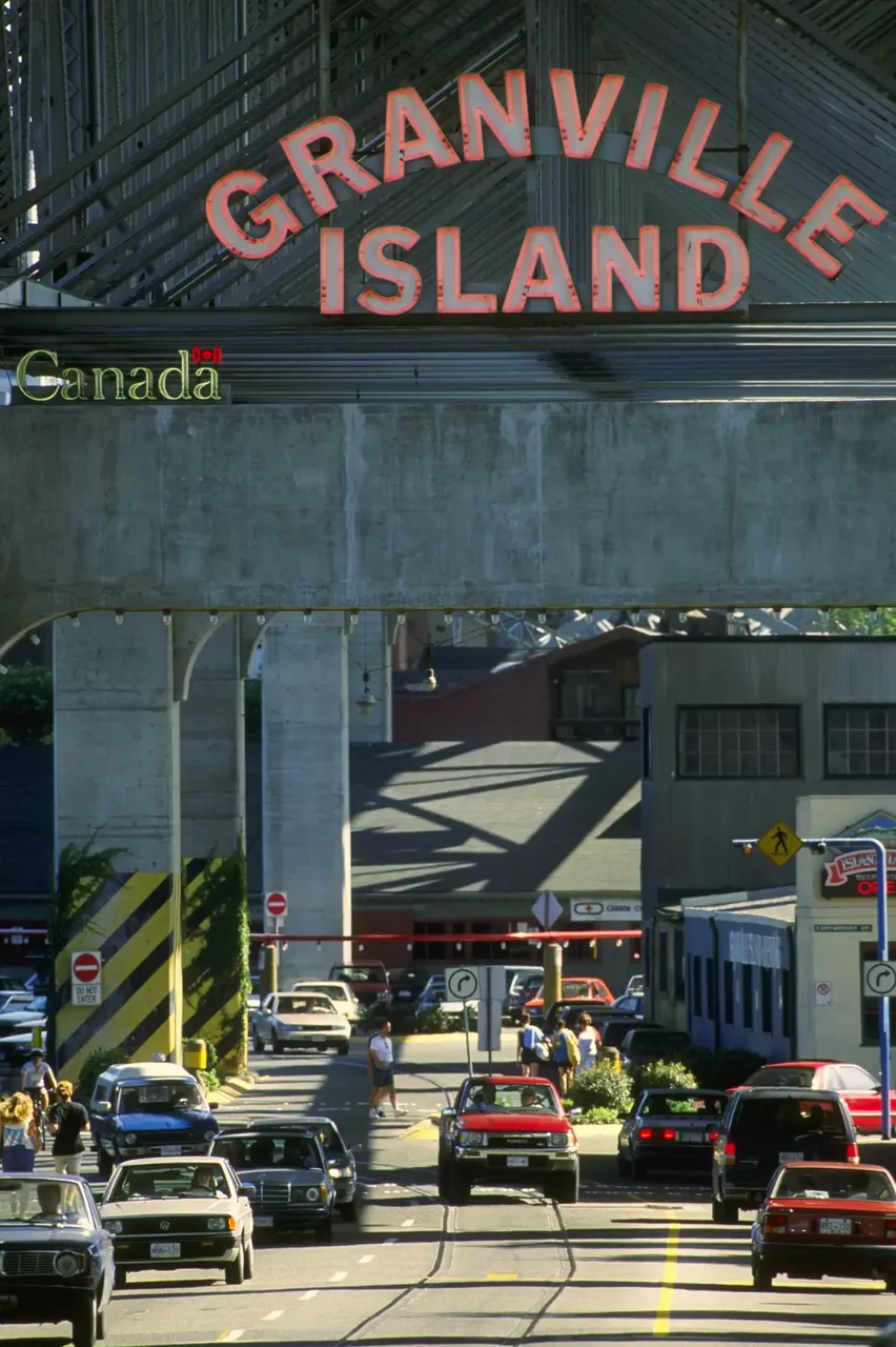 La icónica entrada a Granville Island en Vancouver, con su cartel de neón, y coches y personas debajo