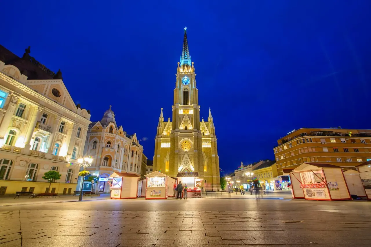 Quiet scene of a closed Christmas market in Novi Sad, Serbia, with wooden stalls lined up under soft lights