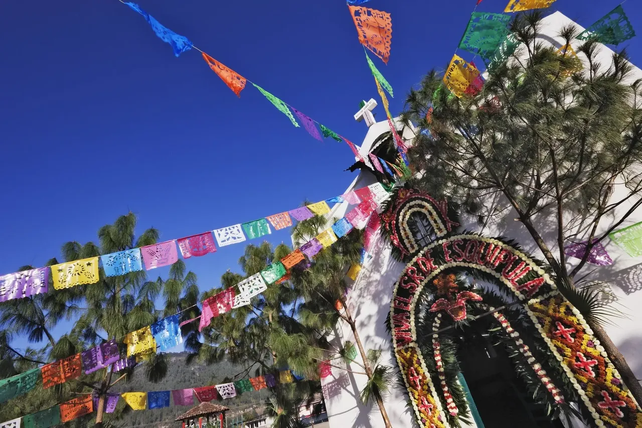 Kolorowe papierowe dekoracje wiszą nad gwarną ulicą w Chiapas, tworząc świąteczną i pełną życia atmosferę.