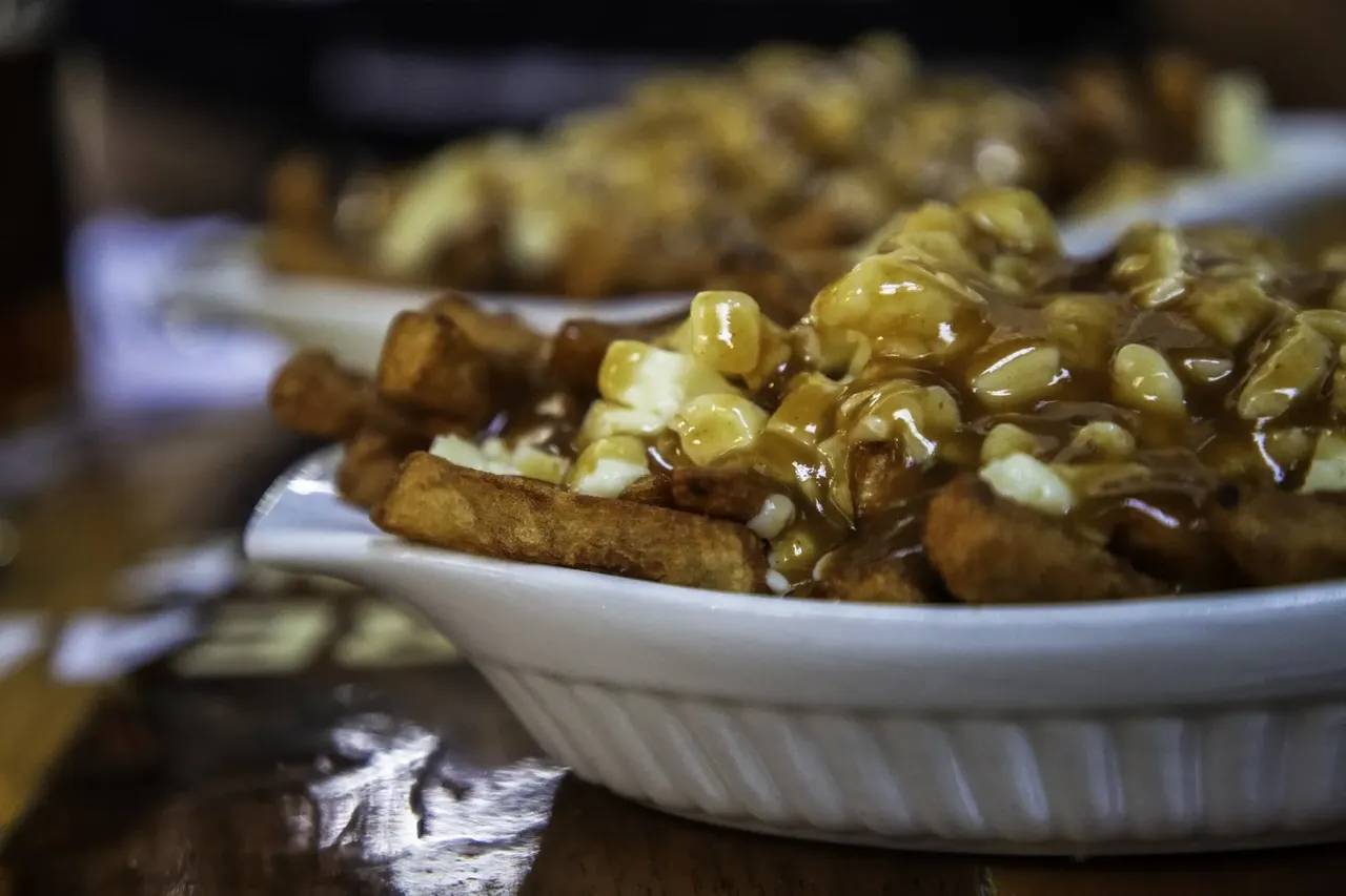 Close-up of a plate of poutine, showcasing crispy fries topped with rich brown gravy and melted cheese curds.