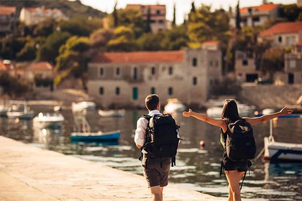Backpacking couple walking along bank of a lake in Europe — Shutterstock