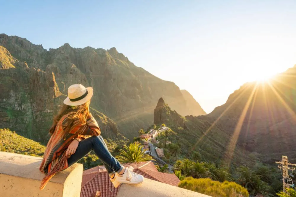 Woman looking at sunset over jagged hills in Tenerife — Getty Images