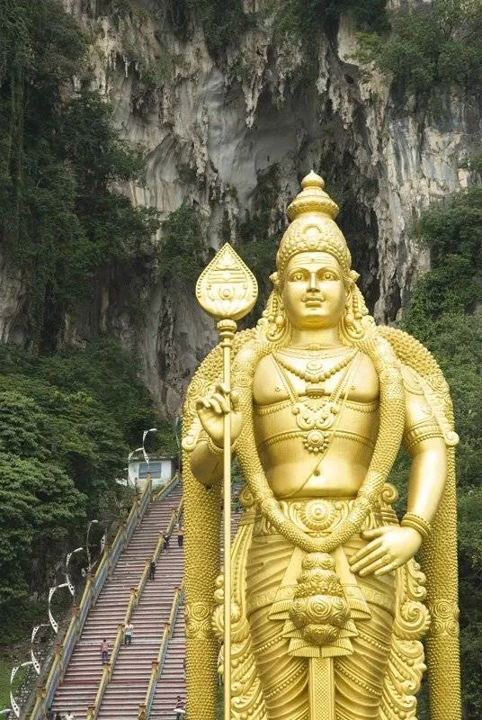 złoty posąg Madrugana w tle schody do jaskini Batu Caves