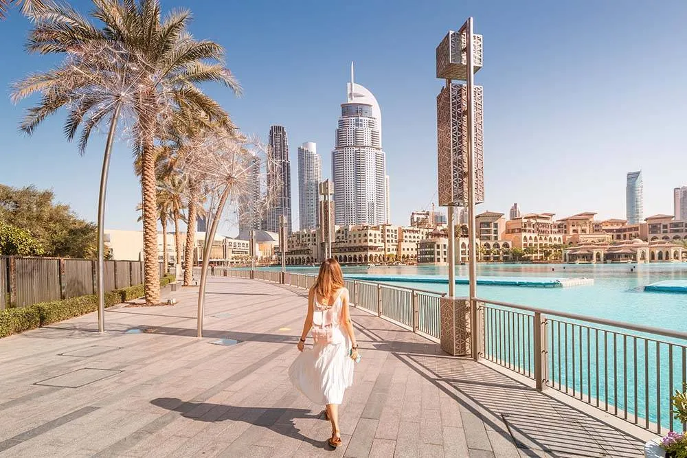 Happy tourist girl walking near fountains in Dubai city