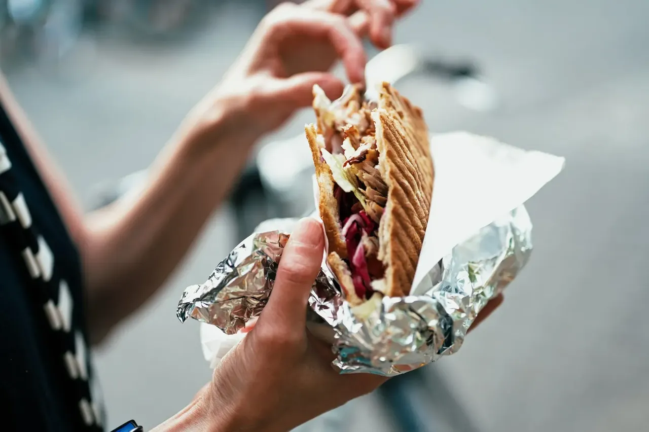 A delicious Döner Kebab, showcasing layers of grilled meat, fresh vegetables, and sauces wrapped in flatbread