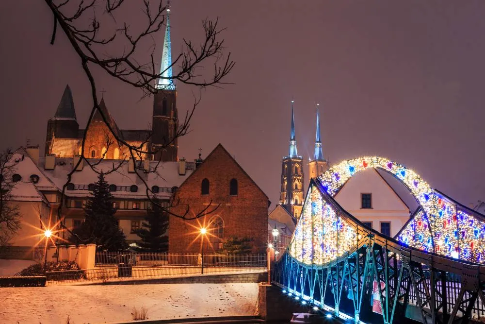 Bridge and church lit up in Wrocław on snowy night — Getty Images