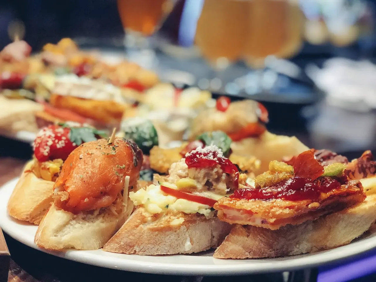 Una colorida bandeja de tapas con tostas de pan cubiertas de varios ingredientes.