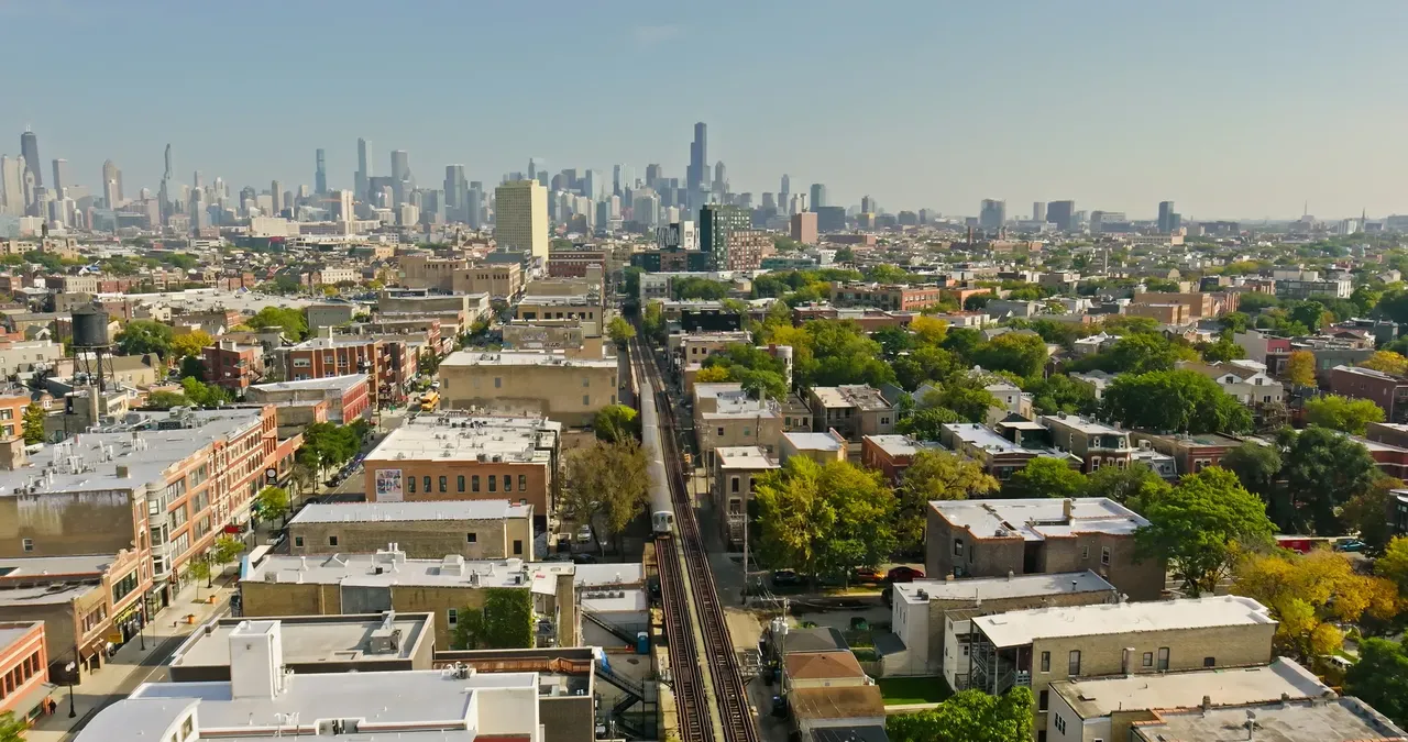 Letecký pohled na čtvrť Wicker Park v Chicagu, který zachycuje ulice lemované stromy, budovy pulzující životem a prolínající se obytné a obchodní zóny.