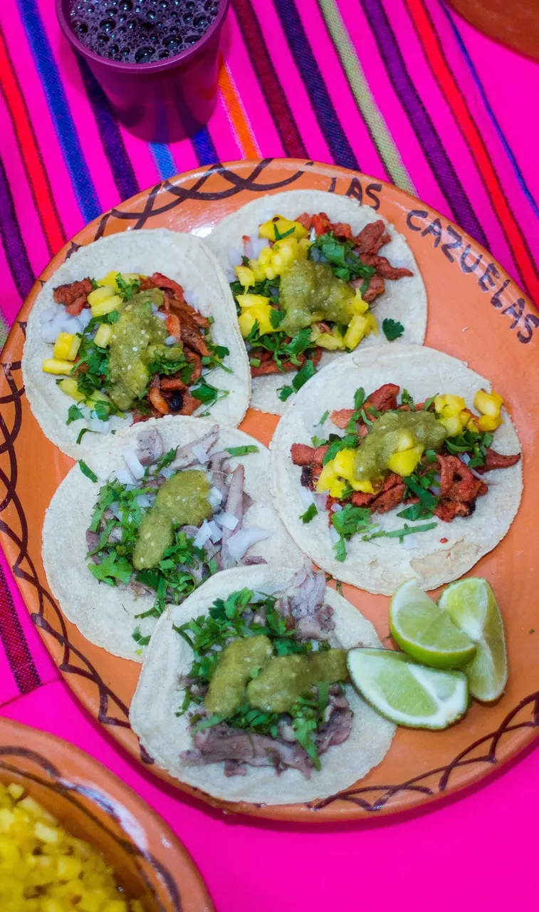 Zbliżenie na pyszne tacos al pastor z marynowaną wieprzowiną, ananasem i świeżymi dodatkami.