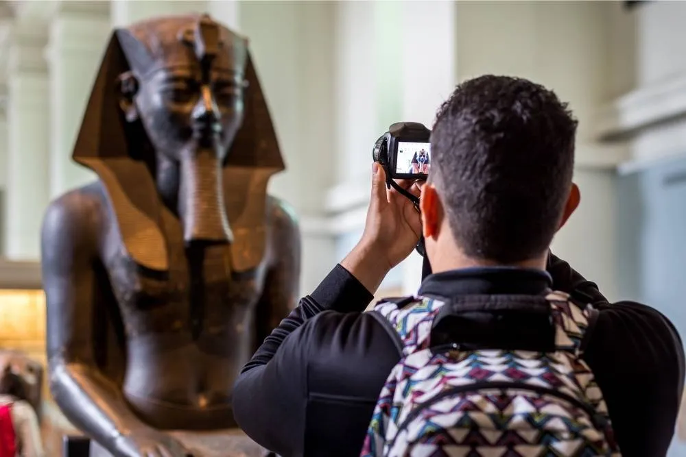 Tourist taking photograph of Ancient Egyptian artifact at the British Museum — Shutterstock