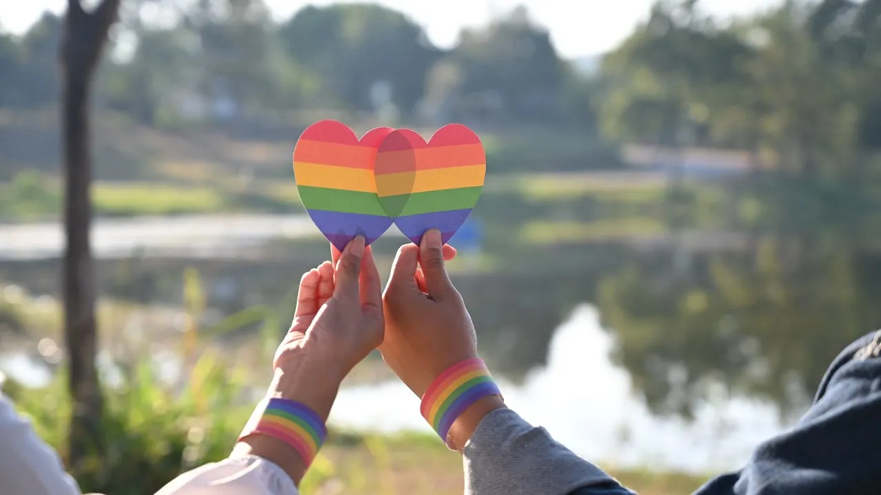 Closeup of LGBT couple while they are holding rainbow hearts on hand. LGBT happiness concept.