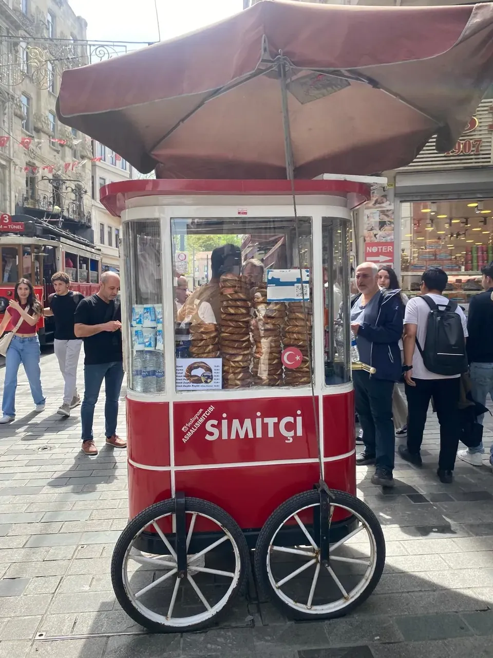 A pile of freshly baked simit, the circular Turkish bread encrusted with sesame seeds, displayed on a street vendor’s cart.