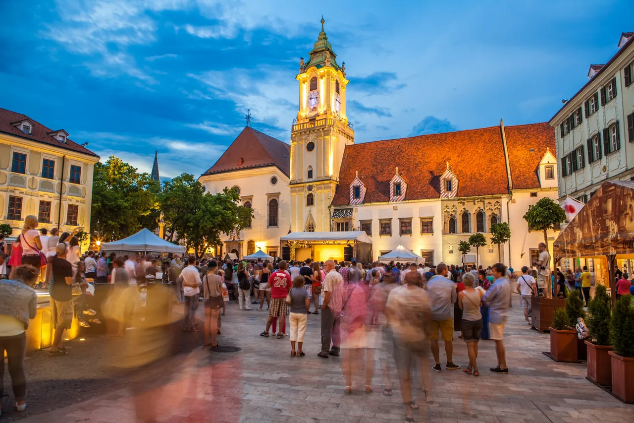 Crowd gathered in Bratislava’s Old Town square during an evening cultural event with the historic Old Town Hall lit up in the background