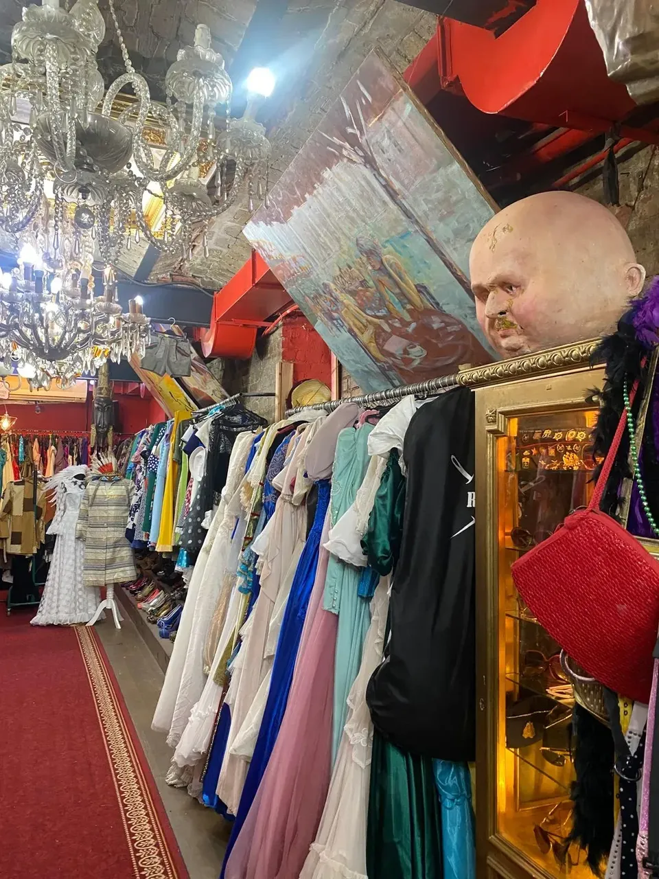 A cluttered vintage shop in Istanbul showcasing an eclectic mix of colorful and quirky clothes hanging on racks and walls, with various accessories scattered around.