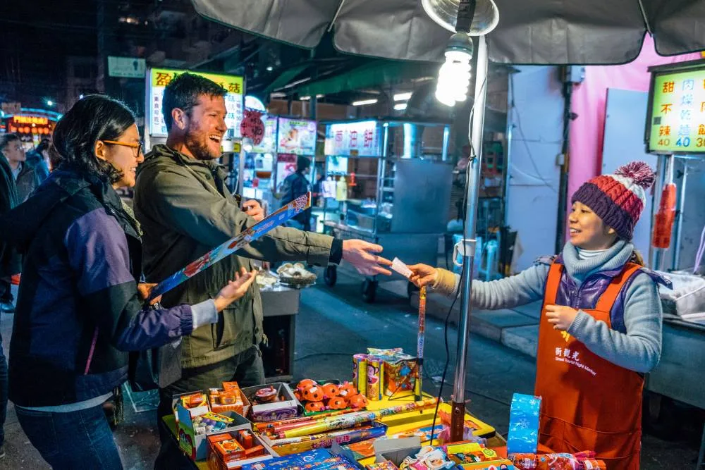 Couple paying for something at Asian street market stall — Getty Images
