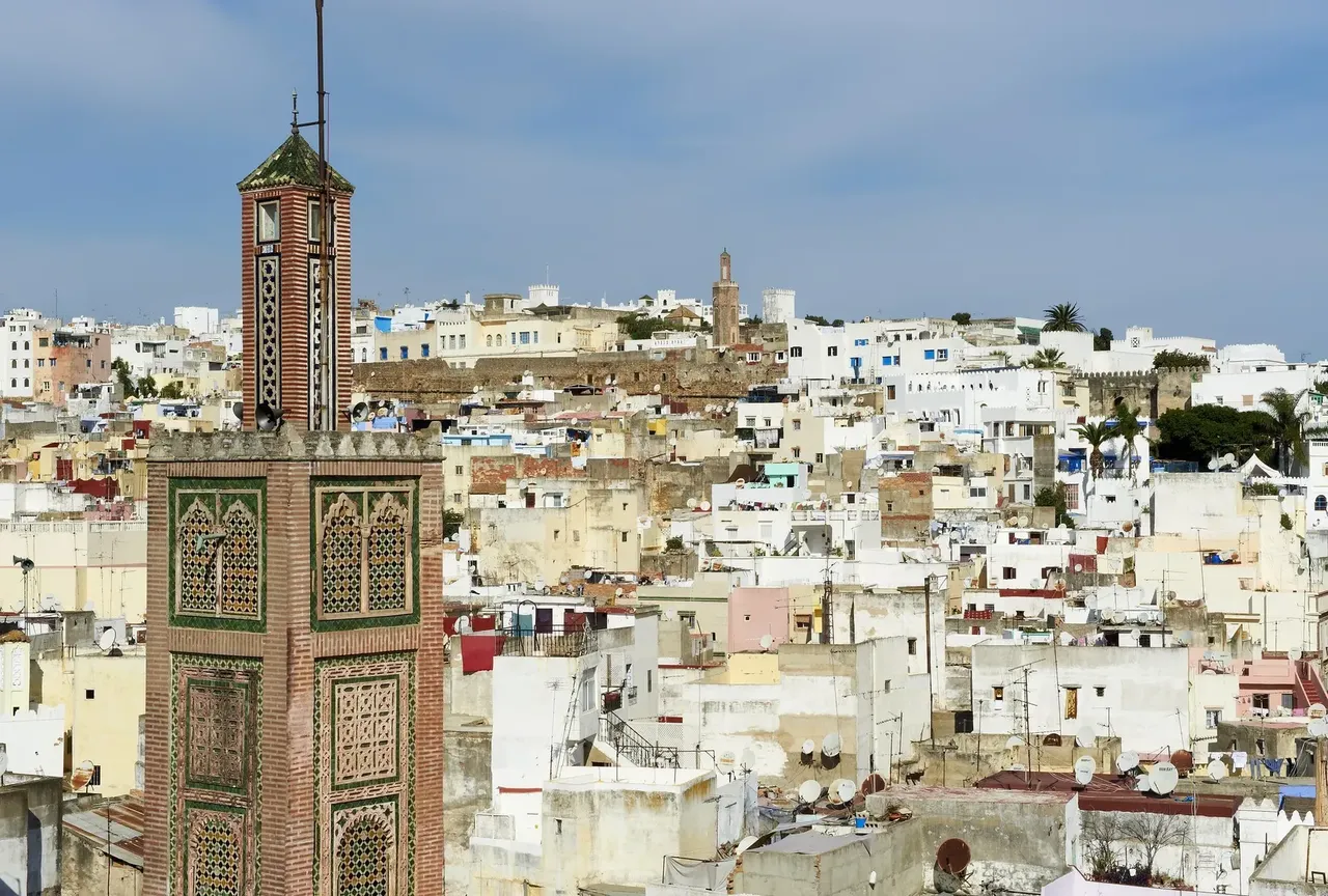 Vista aérea de Tánger con casas blancas y una torre antigua rodeada del paisaje urbano