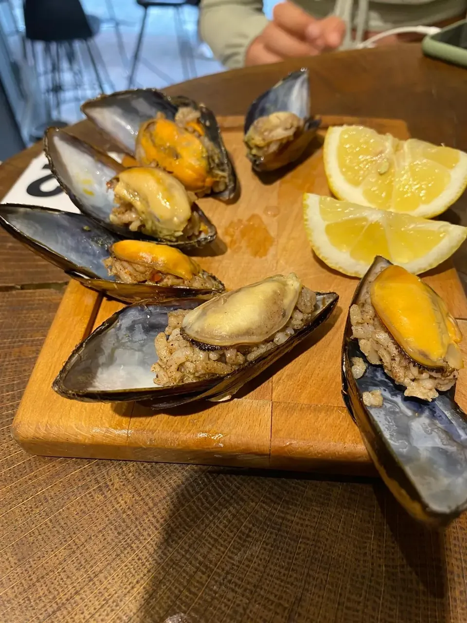 Close-up of a plate of Turkish stuffed mussels, each mussel shell filled with spiced rice and garnished with lemon wedges.