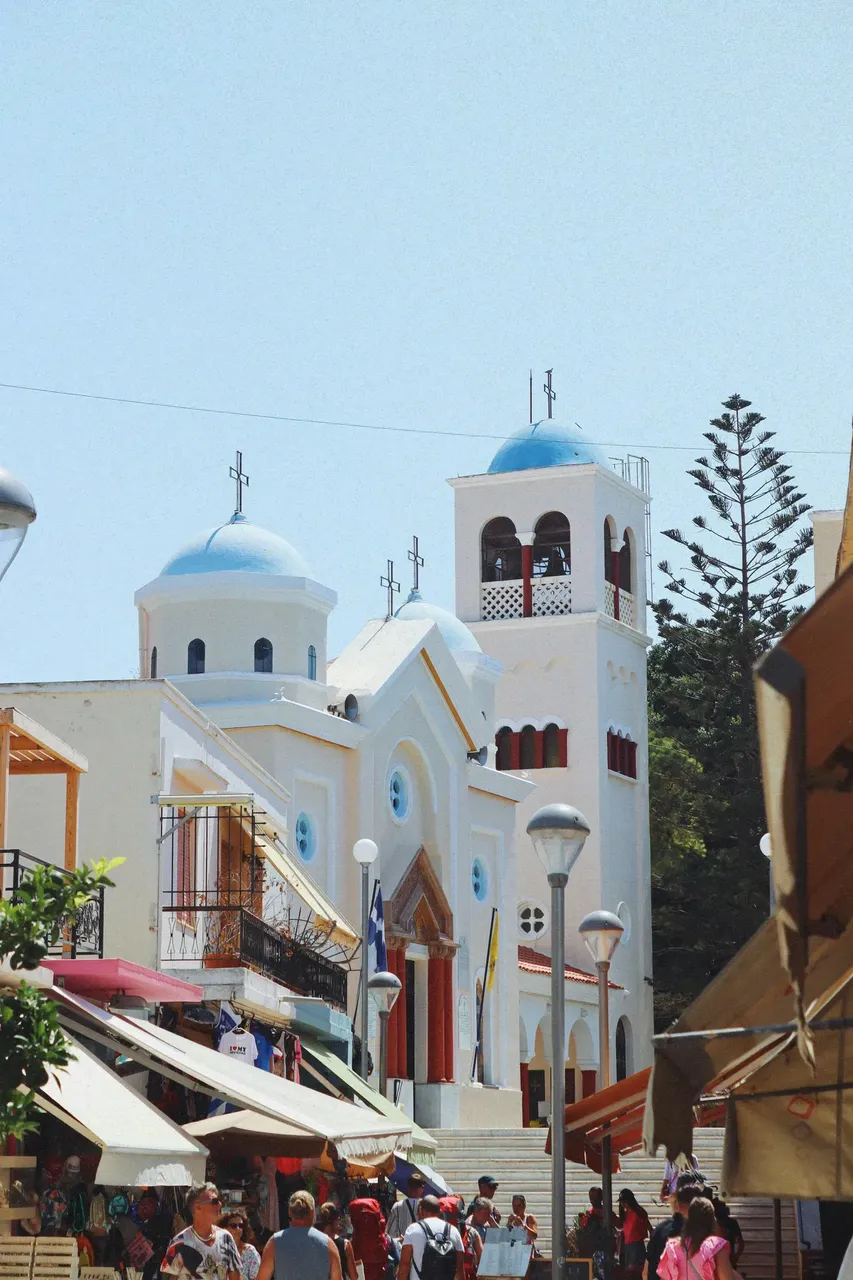 A traditional white house with bright blue doors and windows in Kos, Greece, exemplifying classic Greek island architecture, surrounded by vibrant bougainvillea