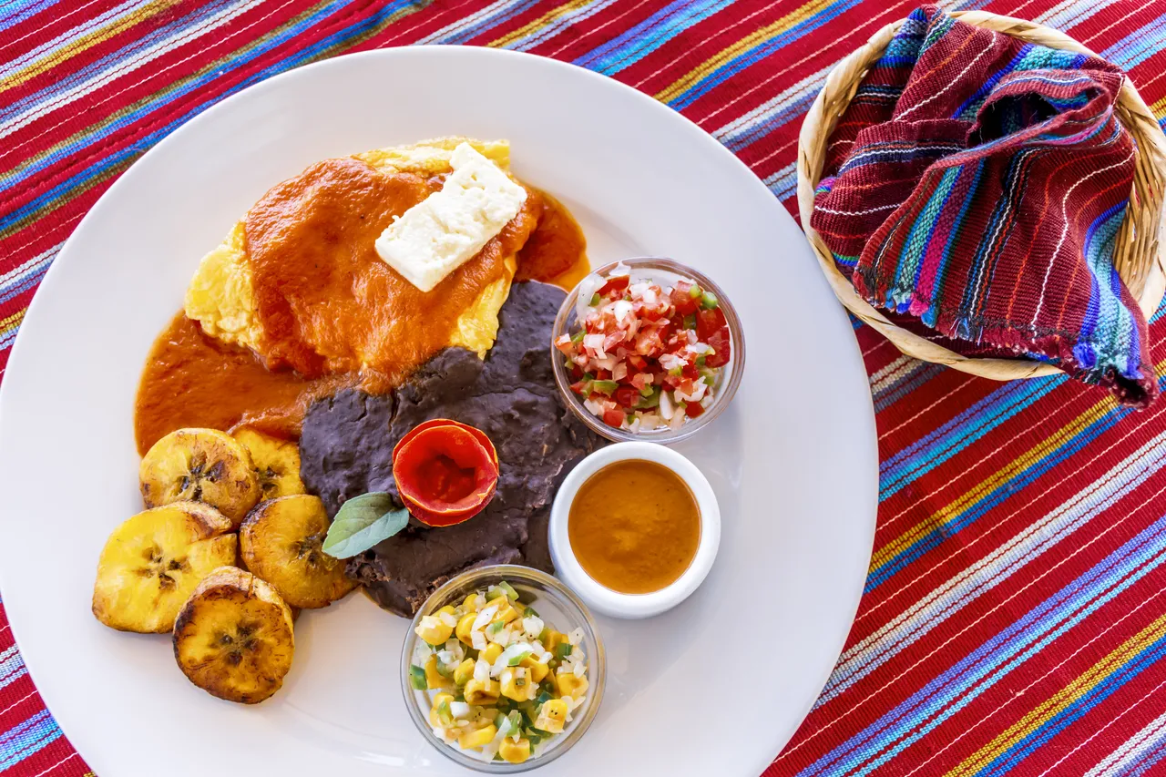 Traditional Guatemalan breakfast of eggs, black beans, cheese & fried plantain with tortillas