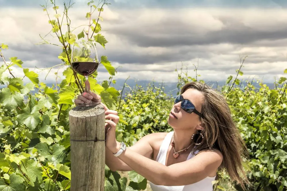 Woman with glass of wine against a vineyard — Getty Images