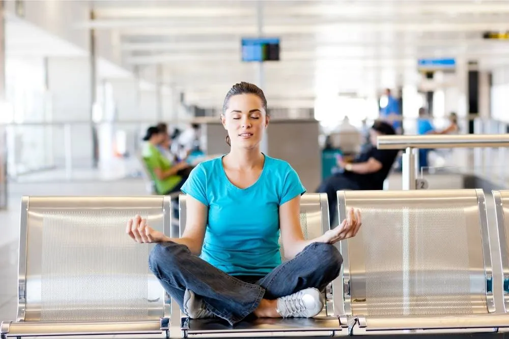 Nő meditál egy reptéri terminál fémülésein