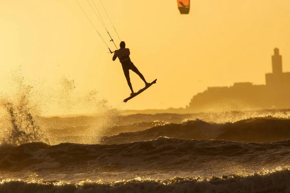 Silhouette of kitesurfer over the waves at sunset — Shutterstock