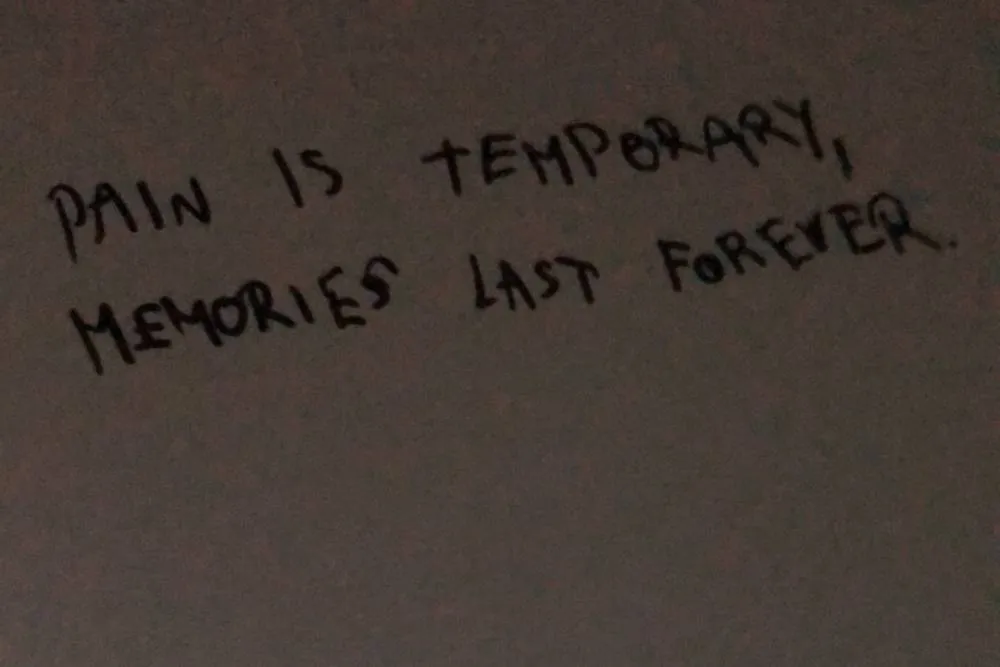 Close-up of a handwritten note on a wall reading ‘Pain is temporary, memories last forever’ — Dorota Žigová
