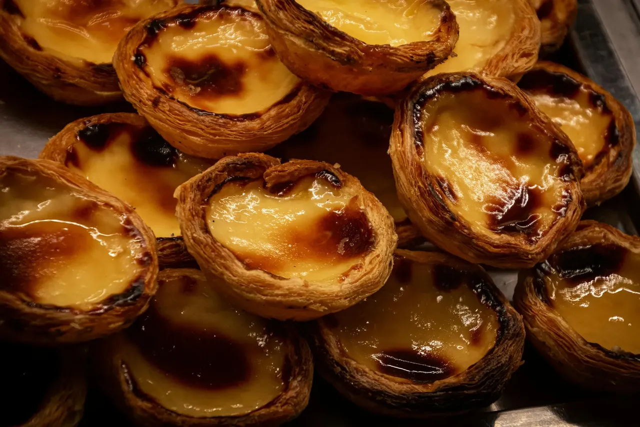 A plate of pastéis de nata, the famous Portuguese custard tarts with golden, flaky crusts and creamy, caramelized centers