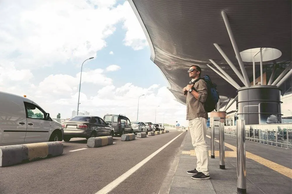 Man with a backpack stood outisde an airport — Shutterstock