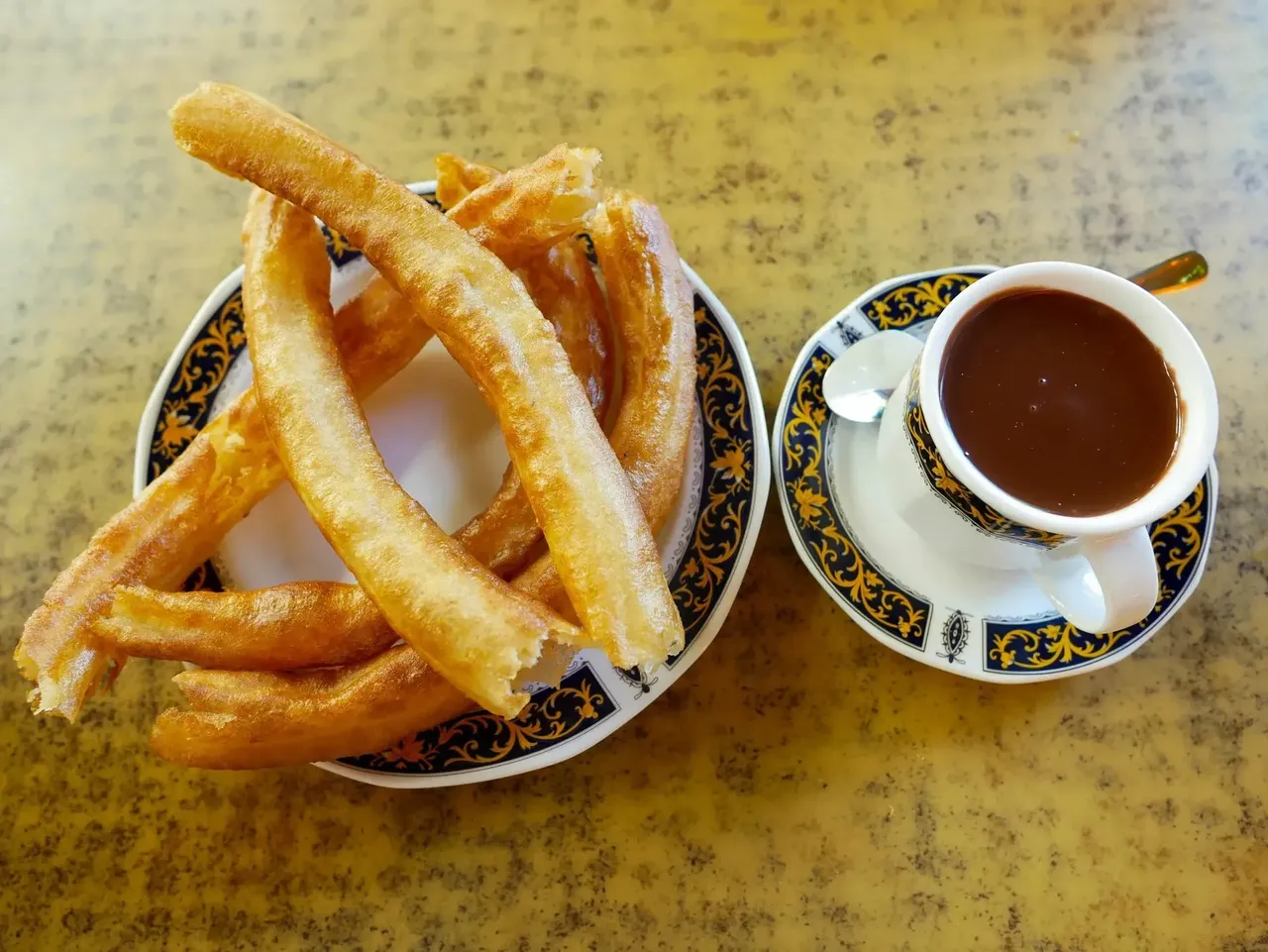 A plate of freshly made churros served with thick, rich chocolate for dipping, a classic Spanish treat.