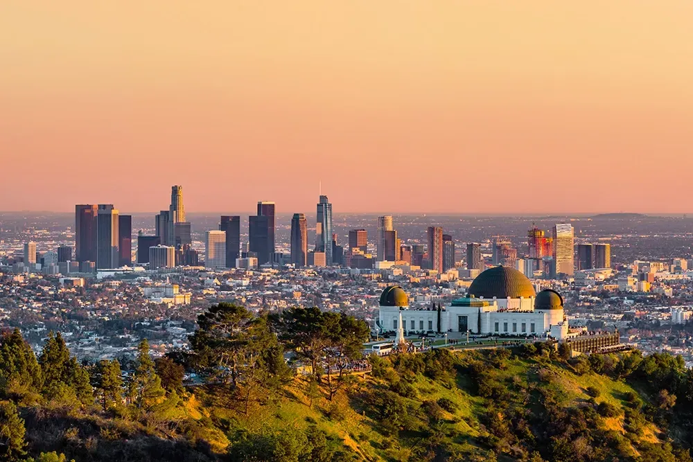 Park z obserwatorium na wzgórzu w Los Angeles o zachodzie słońca, w tle panorama miasta