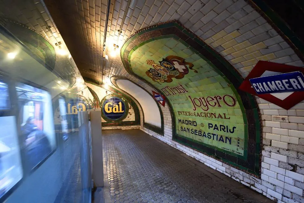 Old Chamberí Metro station platform with modern train passing by — Tim Adams from Madrid, CC BY 2.0, via Wikimedia Commons