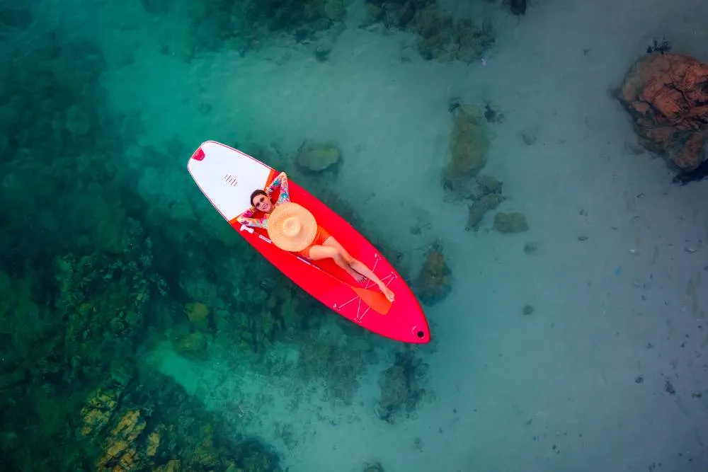 Tânără femeie stă relaxată pe o placă de surf pe mare