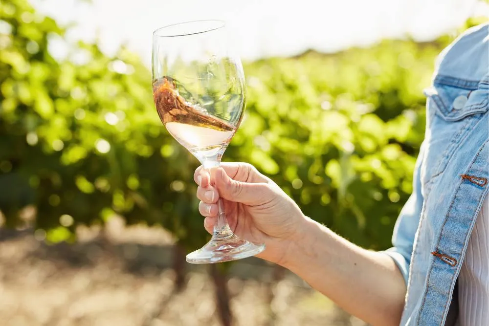 Close-up of wine glass being swirled against vineyard backdrop — Getty Images