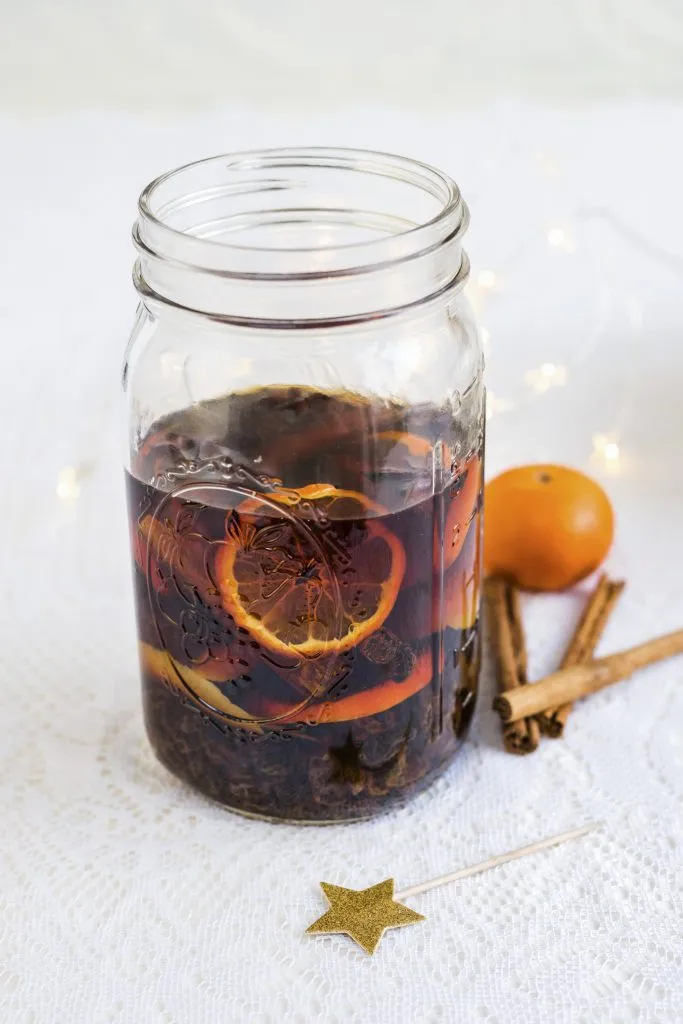 Homemade rum punch with clementines, raisins, cinnamon and lemon zest in a glass jar