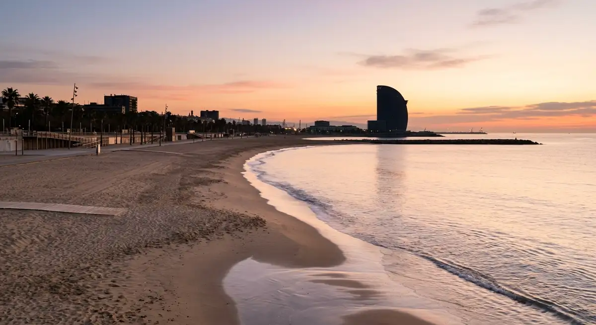 Barceloneta beach in the early morning before the crowds, with the W Hotel at the end of the peninsula and the Mediterranean calm