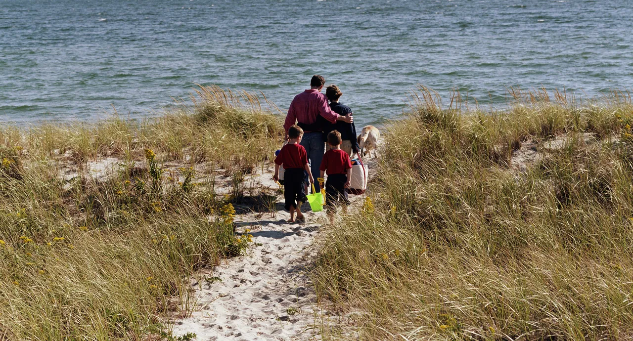 Parents with twin sons and a dog carrying bags to the seaside, U.S.A.