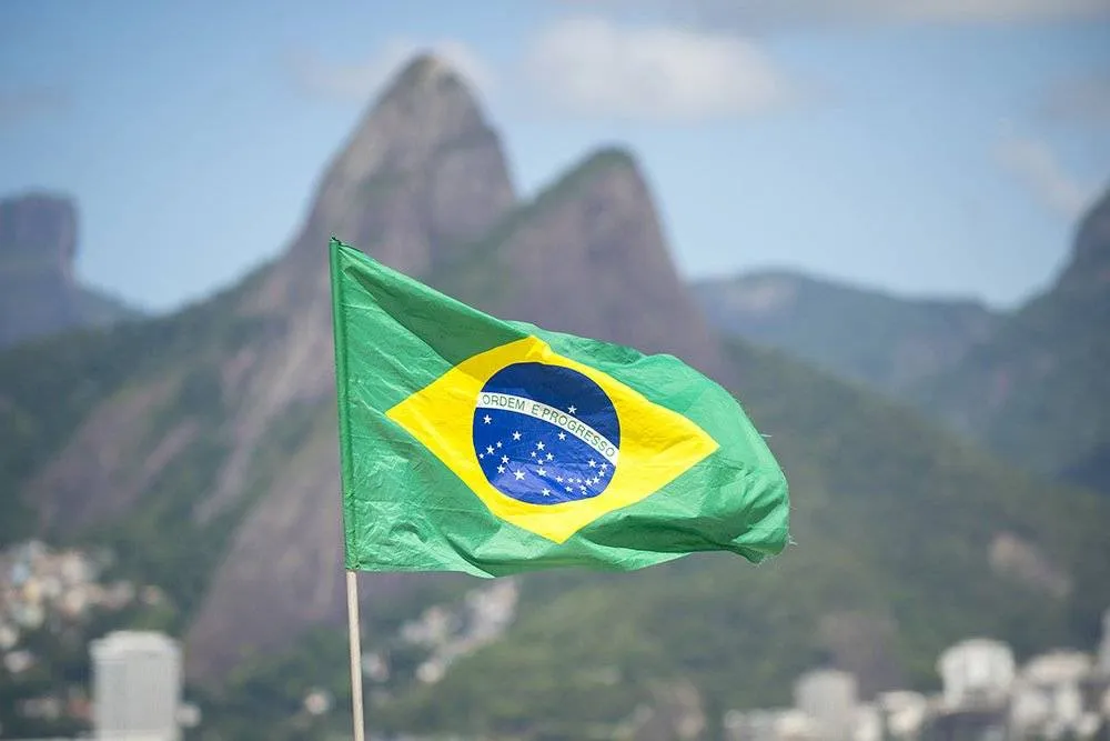 Flaga Brazylii powiewająca na wietrze, na tle góry Dwóch Braci na plaży Ipanema w Rio de Janeiro