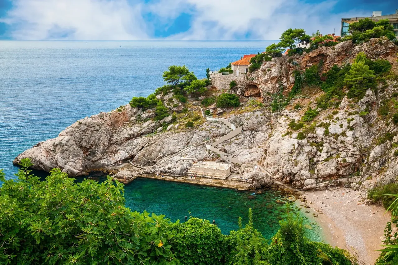 Malebná zátoka s křišťálově čistou vodou a rozeklanými útesy na pláži Bellevue v Dubrovníku