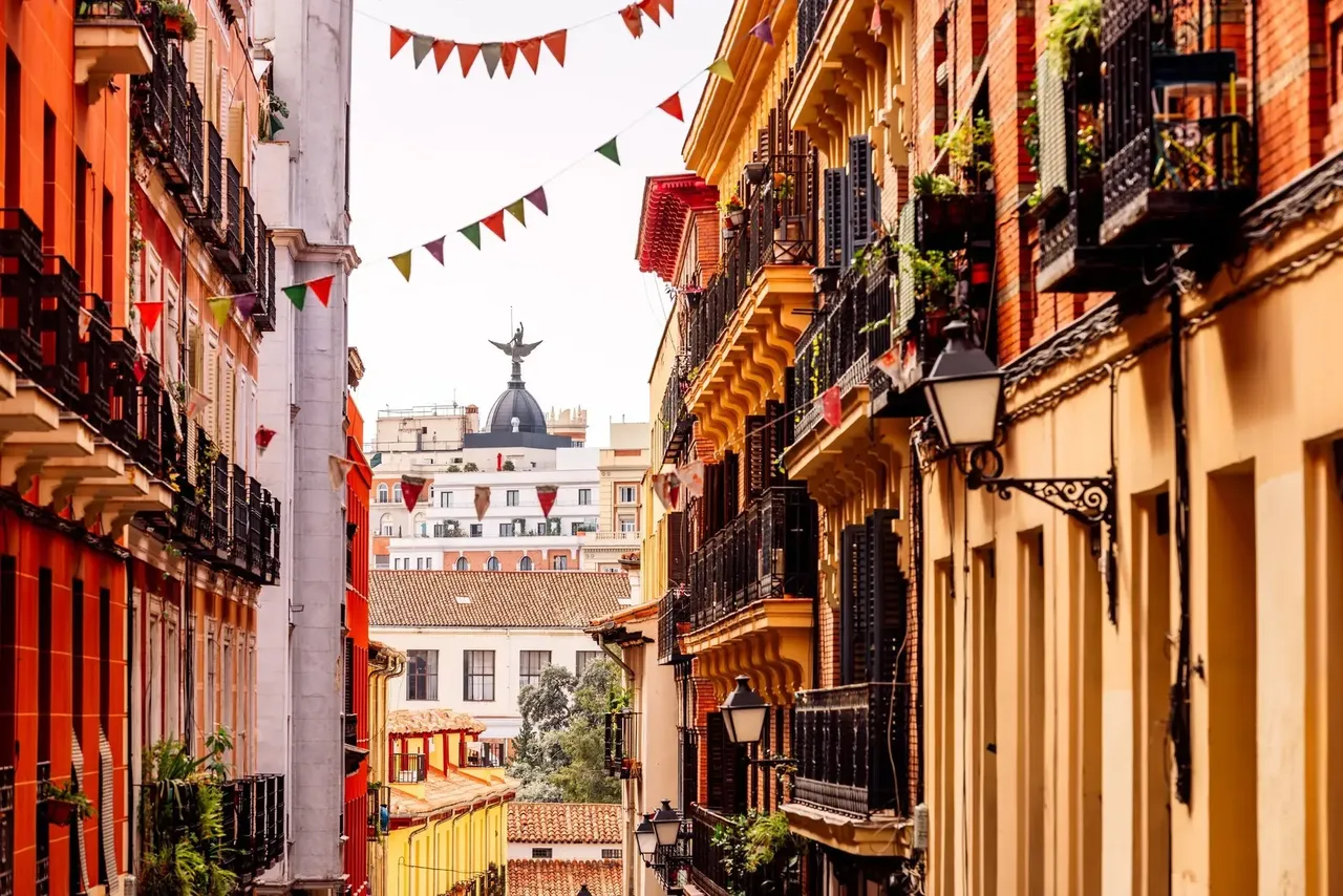Una dinámica calle en Malasaña, Madrid, llena de edificios coloridos y tiendas eclécticas.