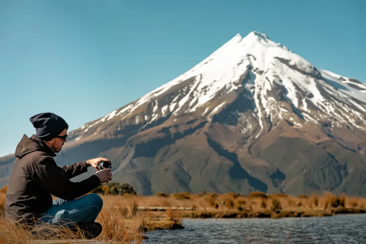 mężczyzna zalewający mate w tle wulkan Taranaki, Nowa Zelandia