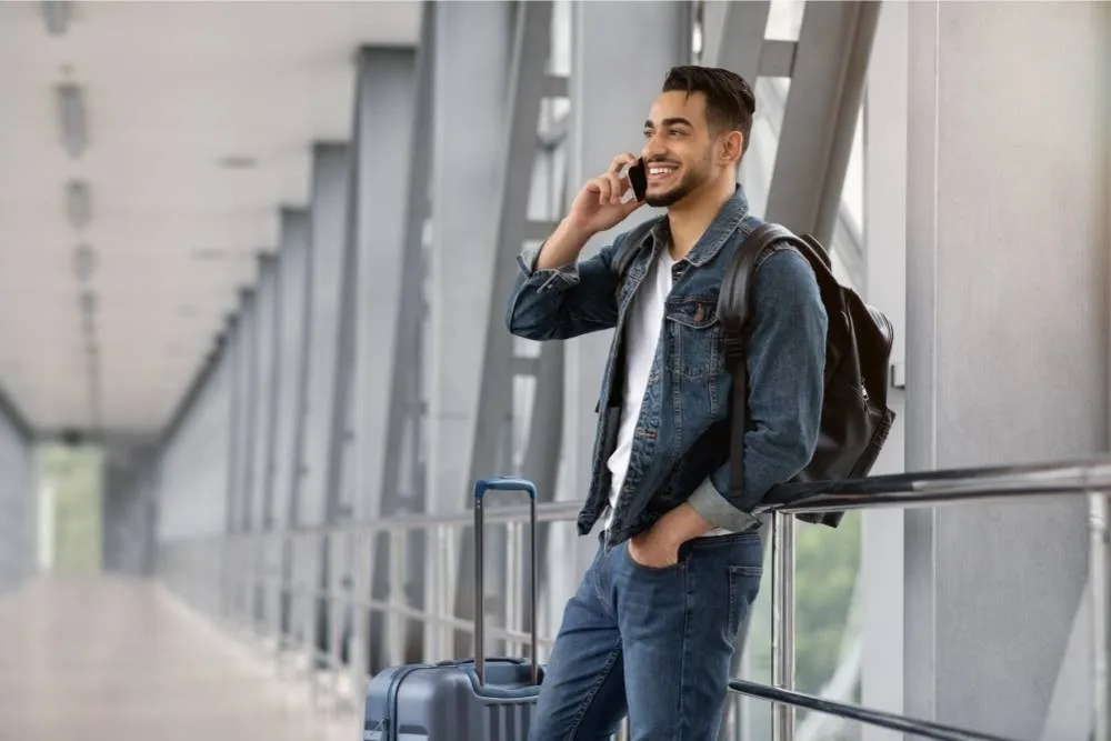 Man on the phone in airport terminal footbridge — Shutterstock
