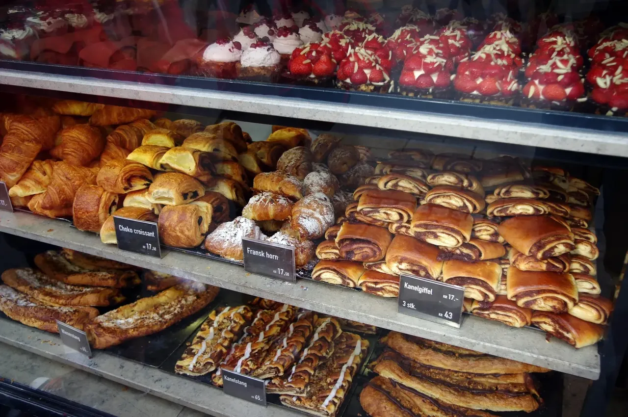 Výloha kodaňské pekárny plná čerstvého dánského pečiva včetně croissantů, skořicových závitků a koláčů s jahodami