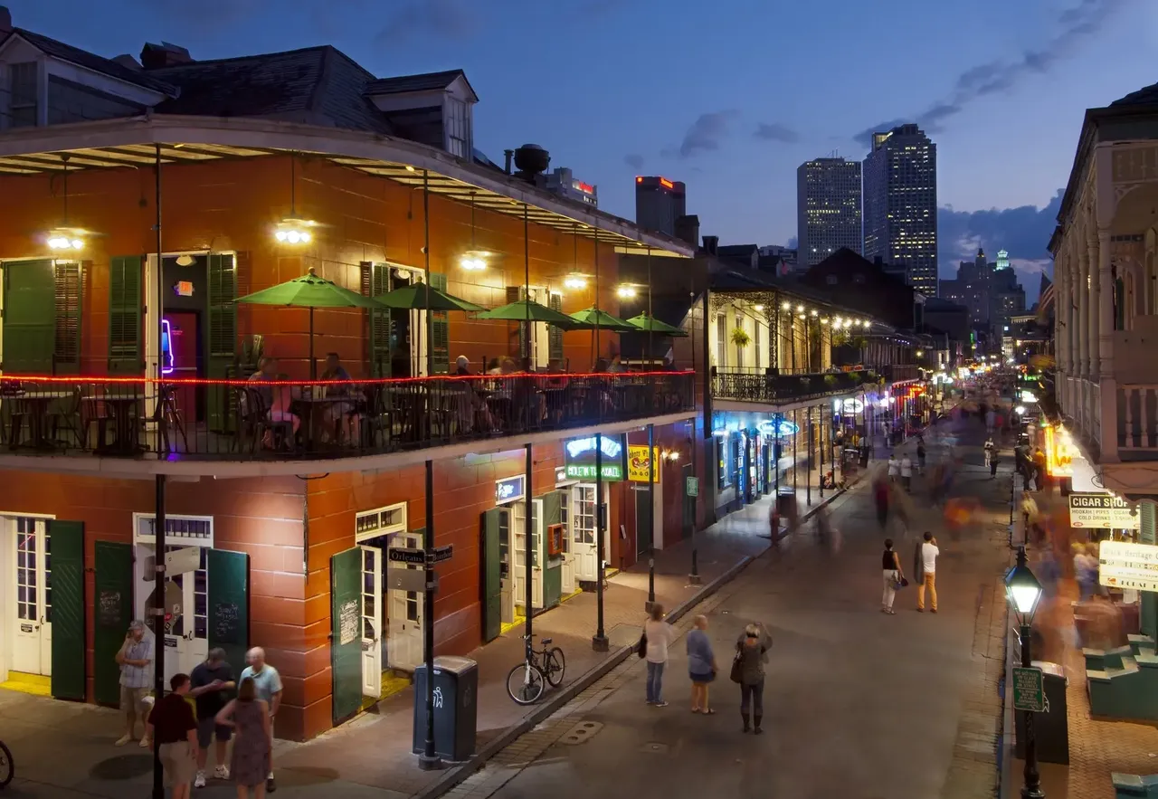 An aerial view of a lively New Orleans street, featuring historic buildings, festive decorations, and the vibrant energy of the city.