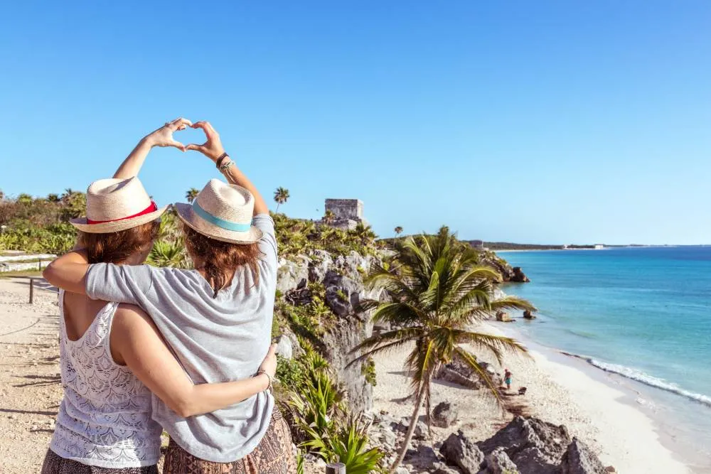Couple making hand heart against beach backdrop in Tulum — Getty Images